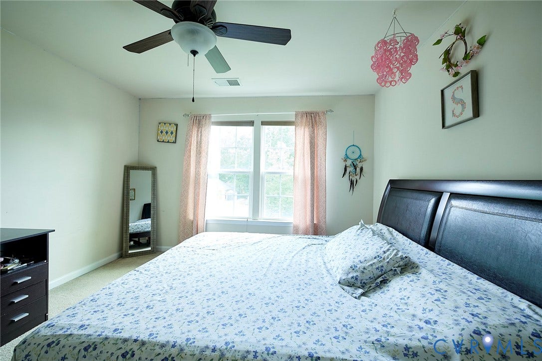 Ceiling fan, window with natural light, wall-to-wall carpeting, neutral wall color, dark wood-finish headboard
