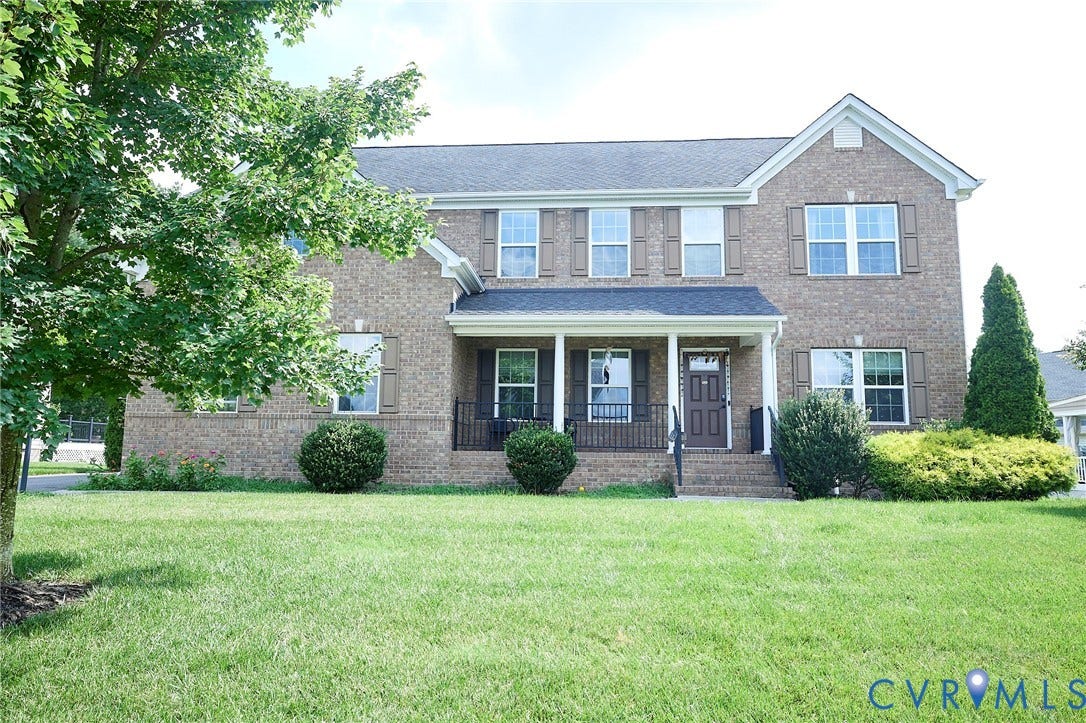Brick exterior featuring a covered front porch with white columns and dark railings
