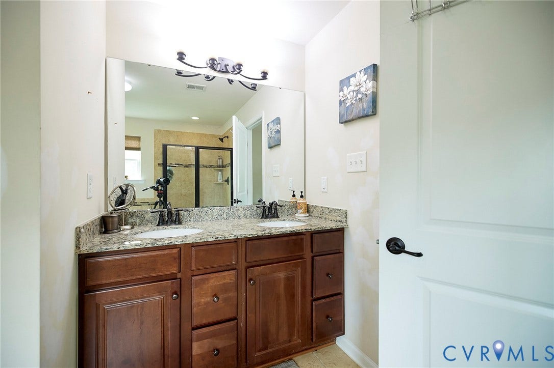 Dual sink vanity with a light-toned countertop and rich wood-finish cabinetry