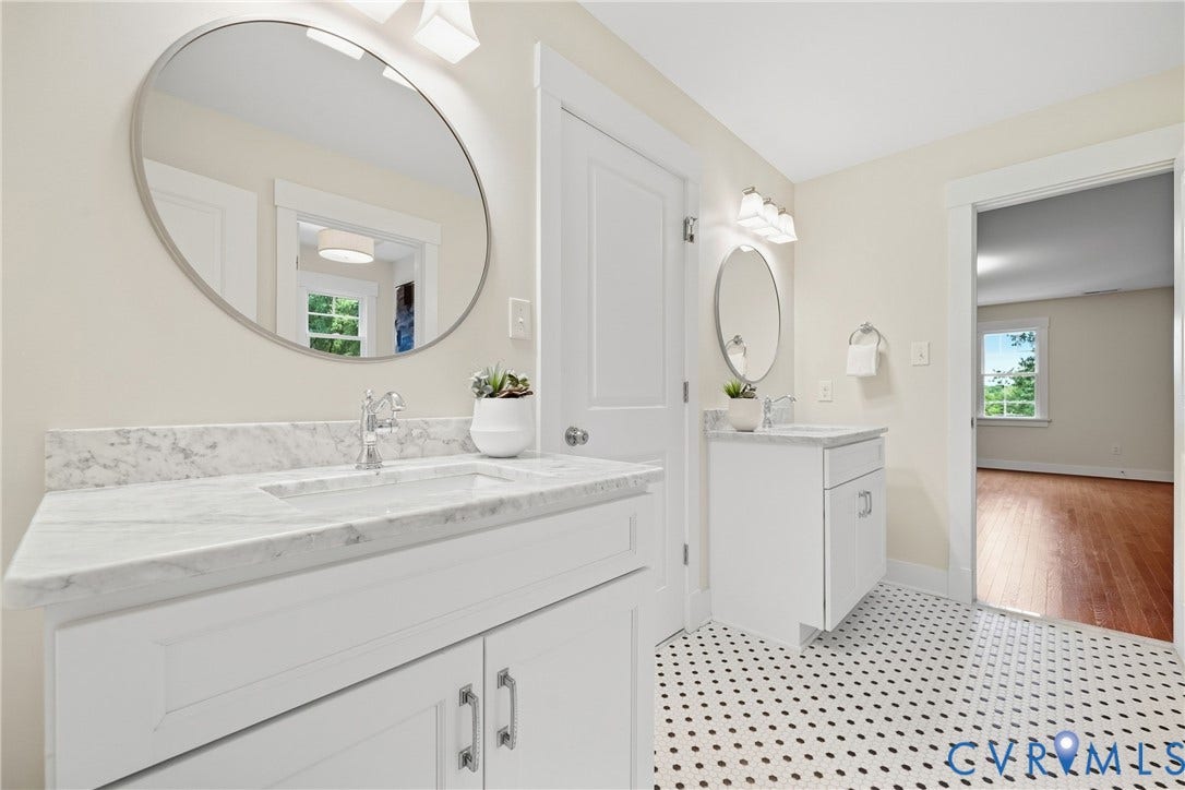 Dual vanity with white cabinetry, integrated sinks, chrome fixtures, and stone-finish countertops