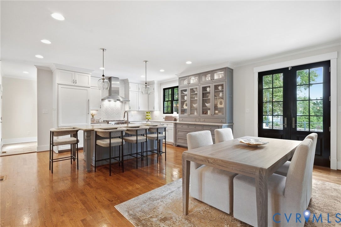Hardwood flooring throughout, kitchen island with seating, stainless steel appliances, built-in display cabinetry, and black-framed French doors