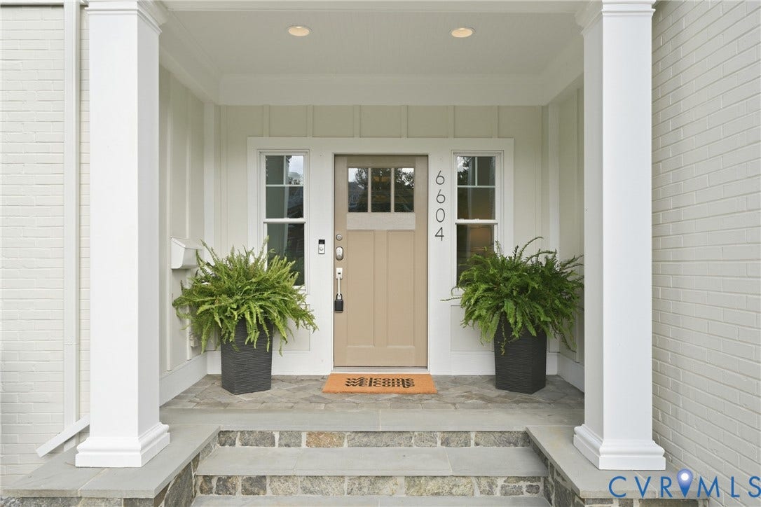 Covered entryway featuring a paneled door with glass inserts, transom window, and flanking sidelight windows