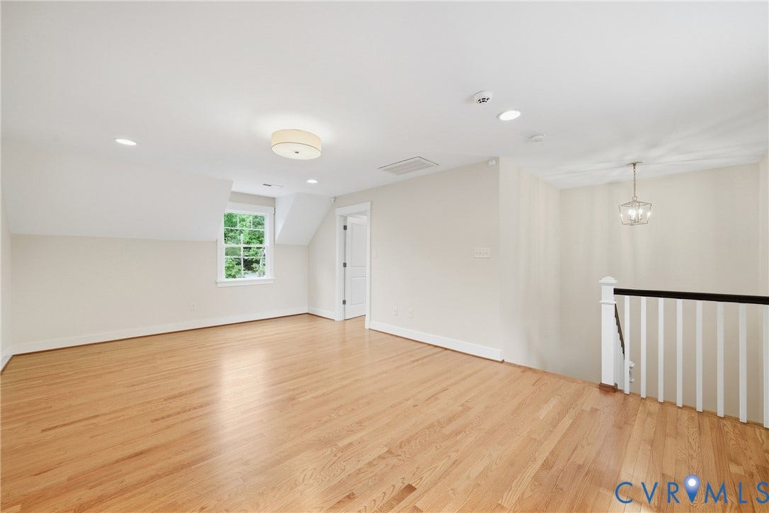 Hardwood flooring, recessed lighting, white trim and walls, exposed wood window, and a white baluster railing with a dark wood top rail