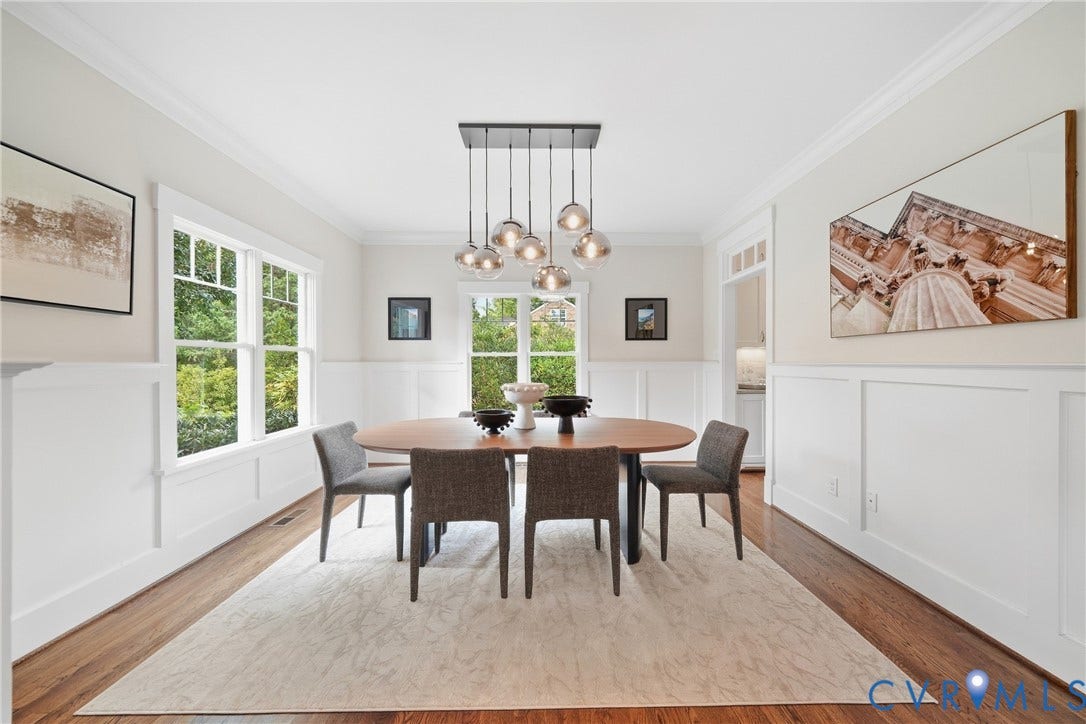 Hardwood flooring, wainscoting, crown molding, double-hung windows, and a multi-pendant light fixture