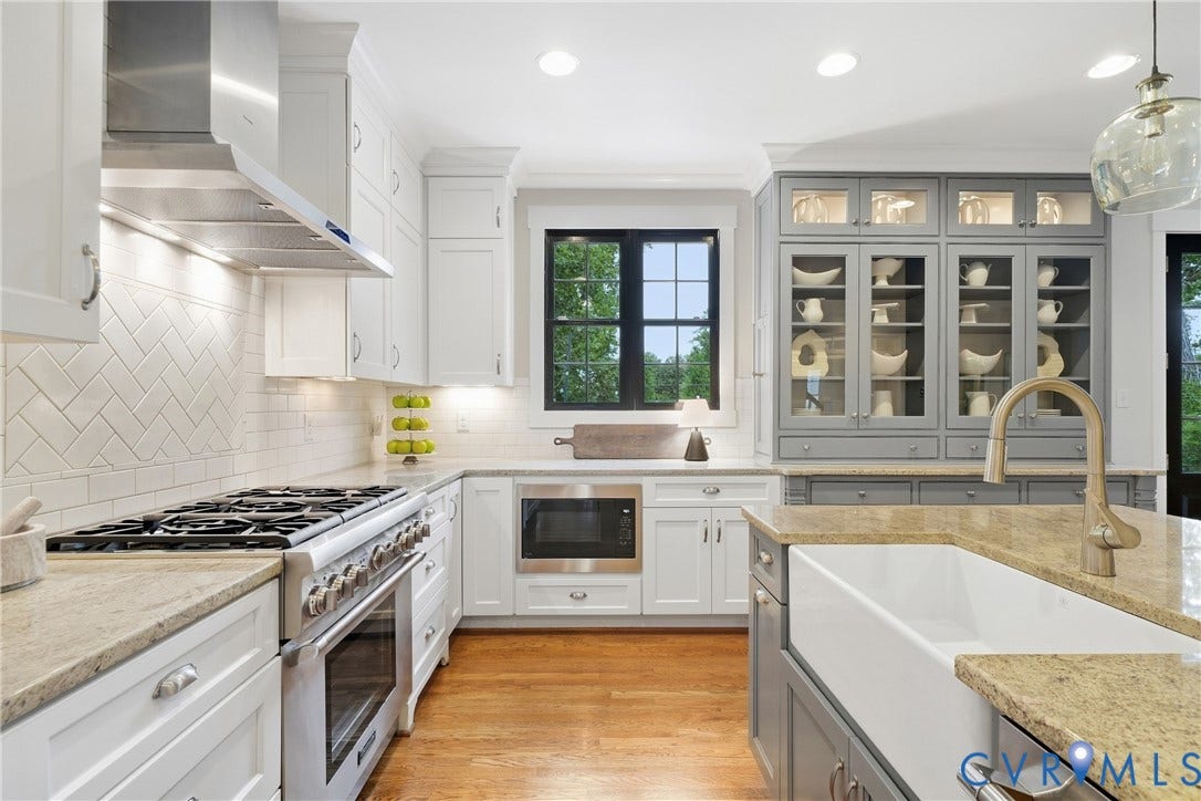 Gourmet kitchen featuring a large range with stainless steel hood, built-in microwave, white shaker cabinetry, a farmhouse sink, and grey built-in display cabinetry