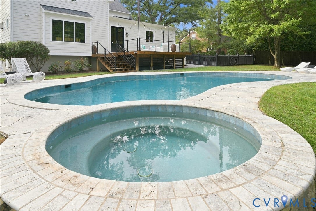 Resort-style backyard featuring a freeform pool, integrated spa, and extensive stone coping