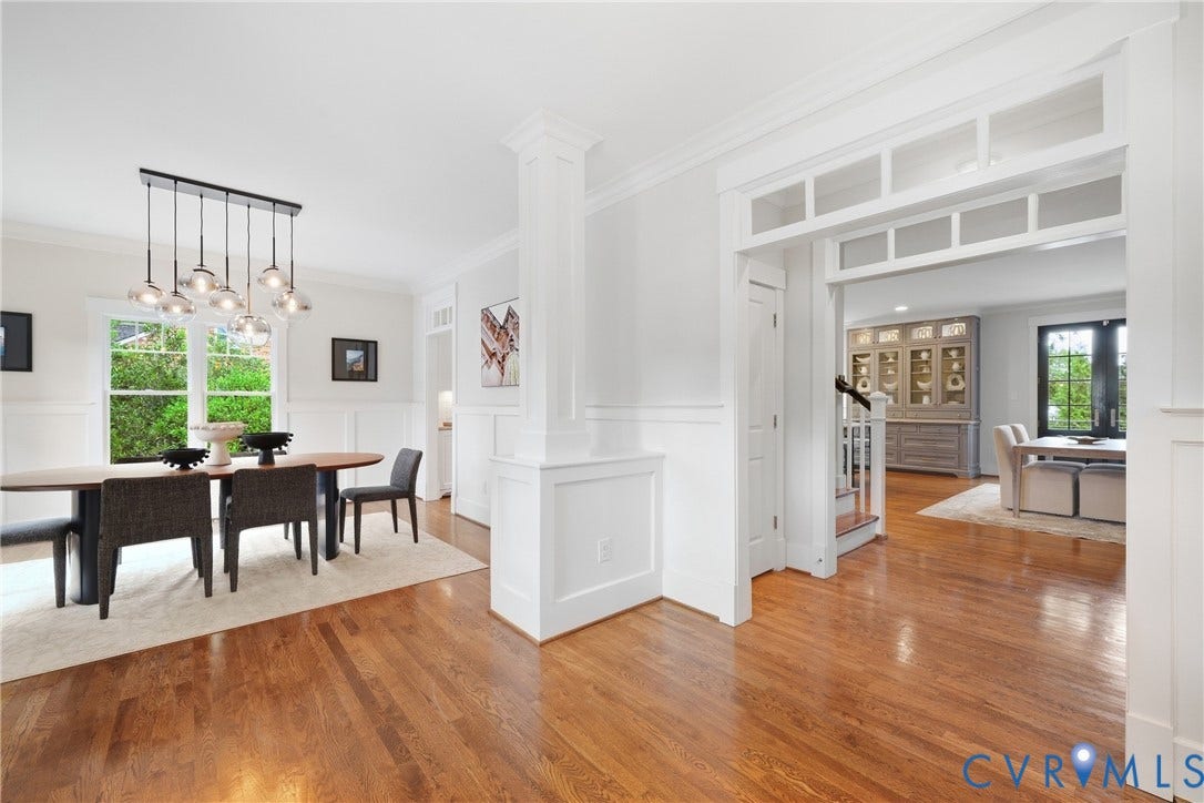 Hardwood flooring throughout, wainscoting, crown molding, transom window-style architectural detail, and a contemporary multi-light pendant fixture