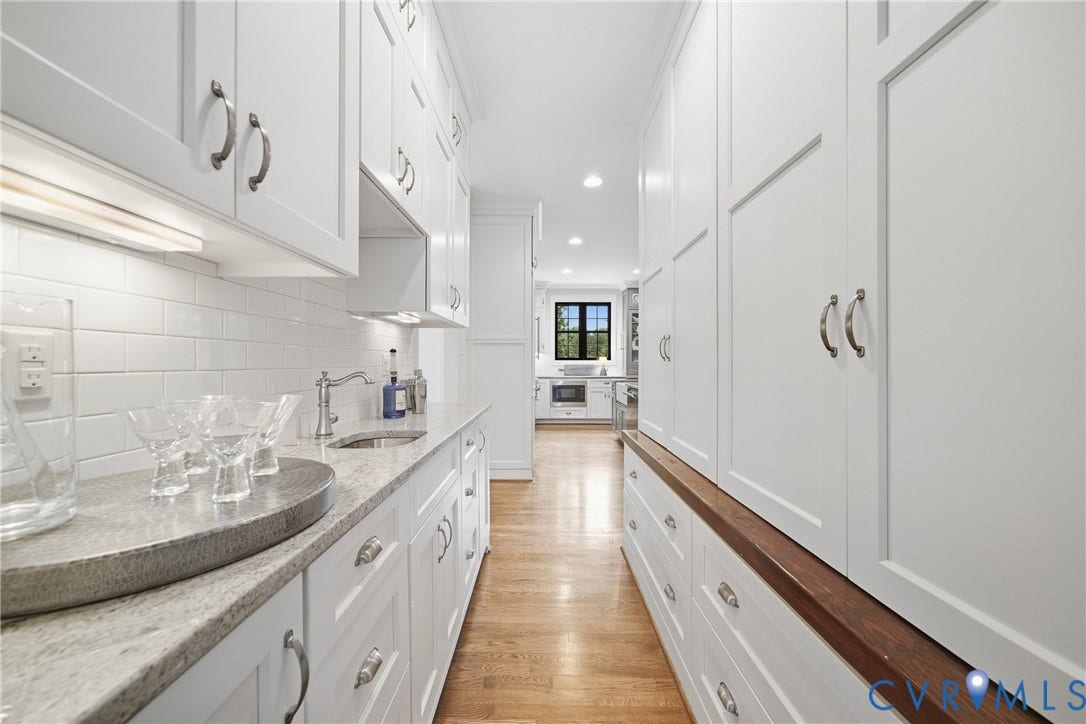 White shaker cabinetry, light-toned countertop, stainless steel sink, wood-finish flooring, and white subway tile backsplash