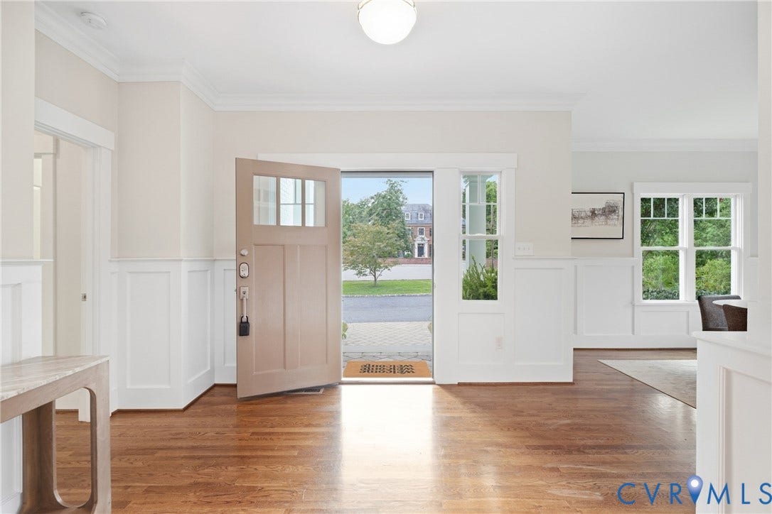 Hardwood flooring, wainscoting, crown molding, transom window, and paneled entry door