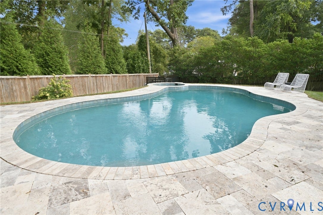 Freeform swimming pool with integrated spa and stone paver surround