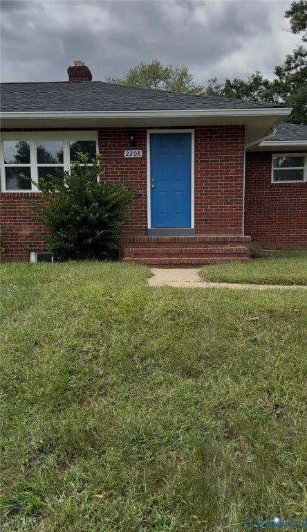 2208 Kirby Road, South Central, Richmond, VA 23224 Red brick exterior featuring a multi-panel blue door, concrete path, and a chimney stack