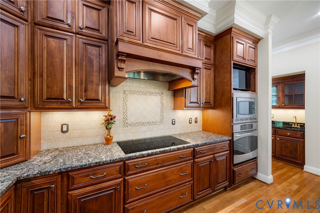628 Cedar Run Road, Hermitage Country Club Area, Manakin Sabot, VA 23103 Rich wood cabinetry with decorative range hood, stone countertops, tiled backsplash with accent detailing, and built-in stainless steel appliances