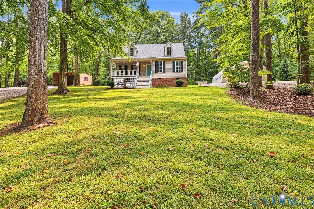 Traditional-style home with a covered front porch, dormer windows, and a gravel driveway