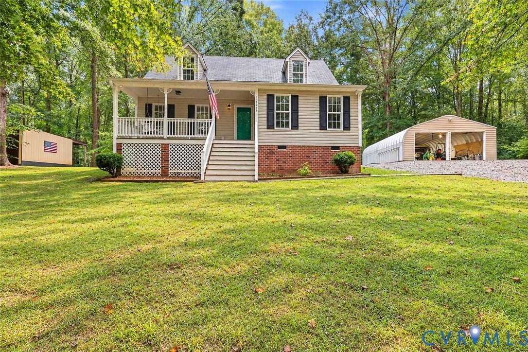 Two-story residence with a covered front porch featuring white railing, dormer windows, and a brick foundation