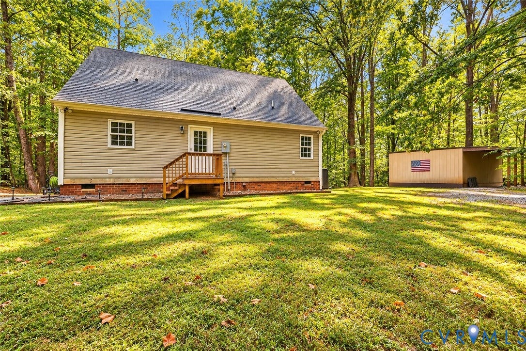 Siding exterior with a shingled roof, brick foundation, and an outdoor deck with wood railings