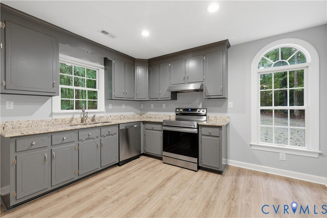 Kitchen with gray cabinetry, light granite-style countertops, stainless steel appliances, and wood-finish flooring