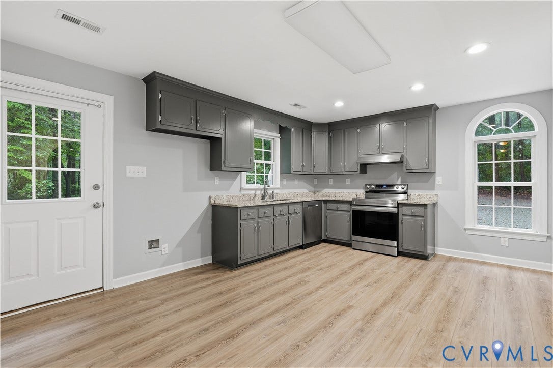 Kitchen featuring wood-finish flooring, gray cabinetry, stainless steel appliances, and a half-round window