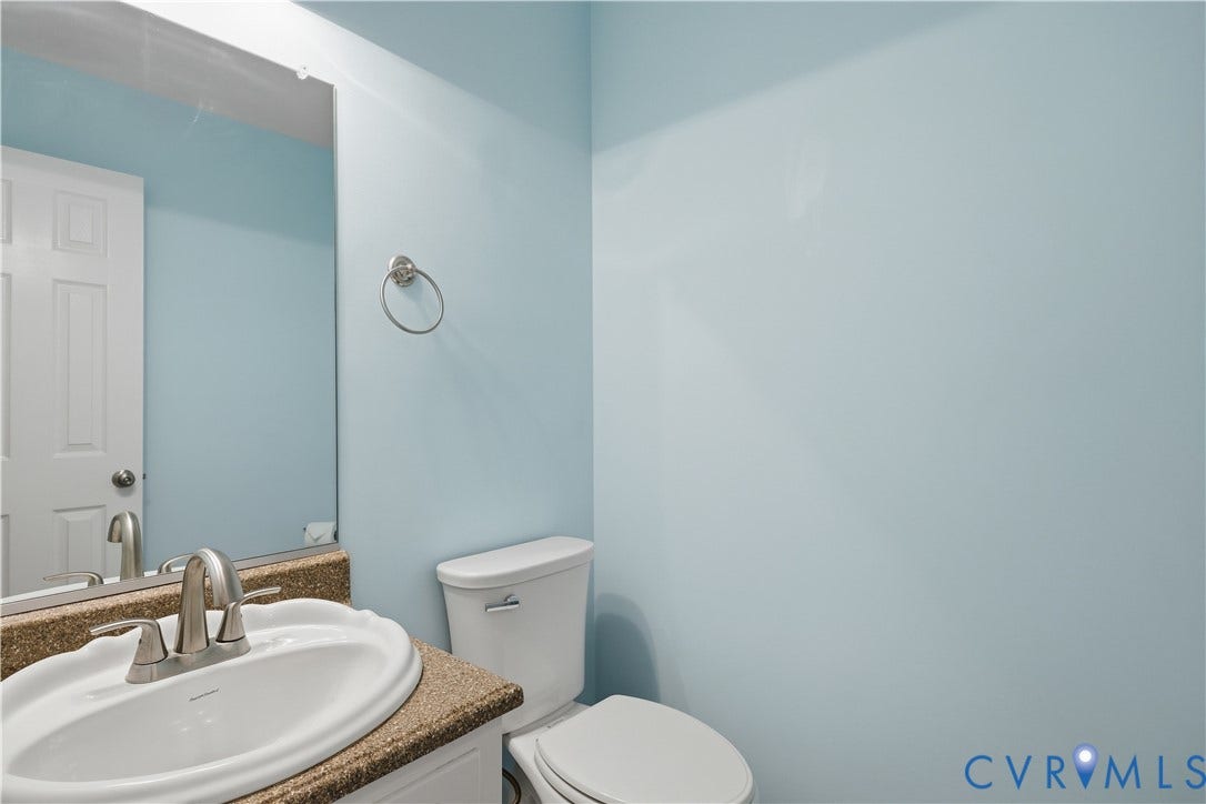 Pedestal sink with a brushed nickel faucet, large wall mirror, and two-piece toilet