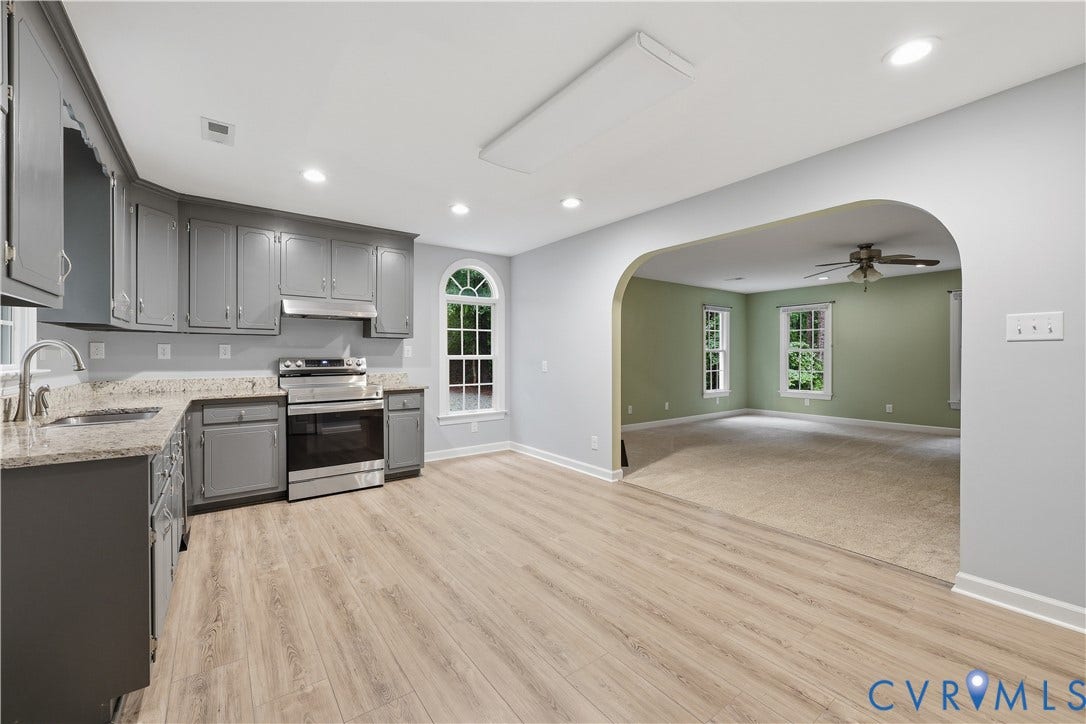 Kitchen featuring gray cabinetry, light granite countertops, stainless steel range with hood, and wood-finish flooring