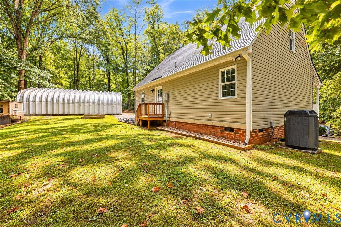 Expansive lawn area with a large arch-style outbuilding, a wooden deck, and mature trees providing natural shading
