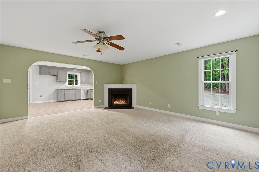 Living area featuring a fireplace with a white mantel, ceiling fan, recessed lighting, and a window
