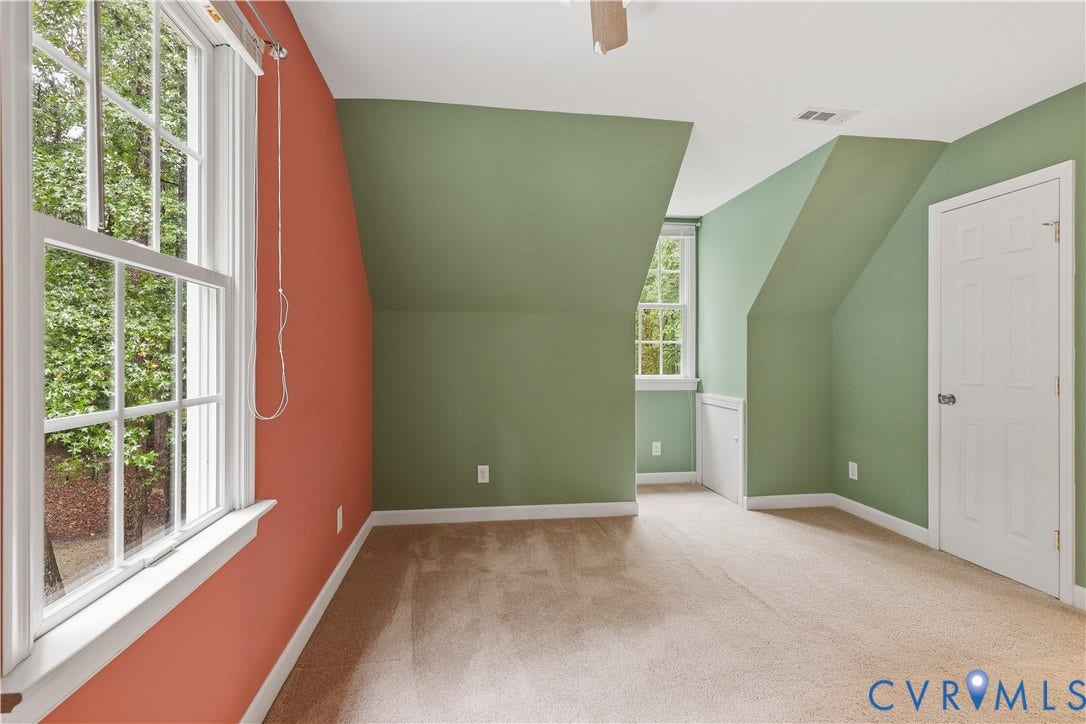 Carpeted room featuring multiple windows, sloped ceilings, and a paneled door