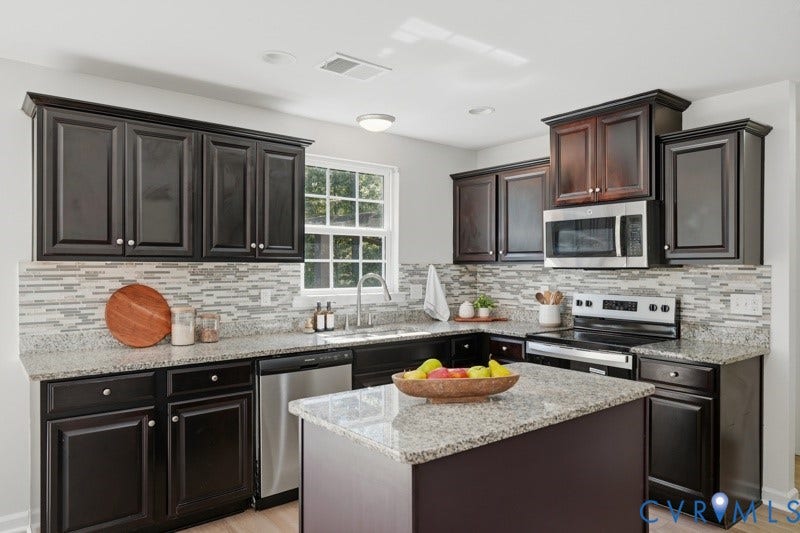 6012 Regal Crest Drive, Kings Grove, Chesterfield, VA 23832 Kitchen featuring dark wood-finish cabinetry, light speckled countertops, a tile backsplash, stainless steel appliances, and a central island