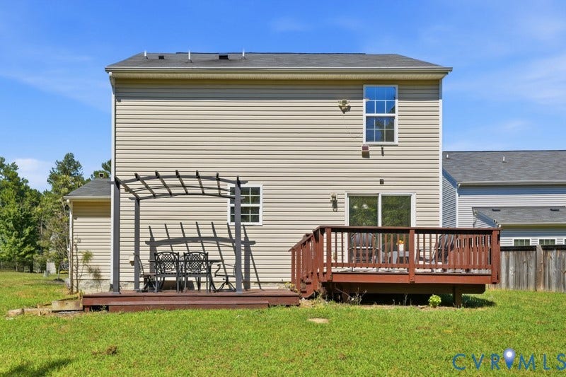 6012 Regal Crest Drive, Kings Grove, Chesterfield, VA 23832 Exterior featuring tan siding, a brown wood-finish deck, a metal pergola, sliding glass doors, and a second-story window with grilles
