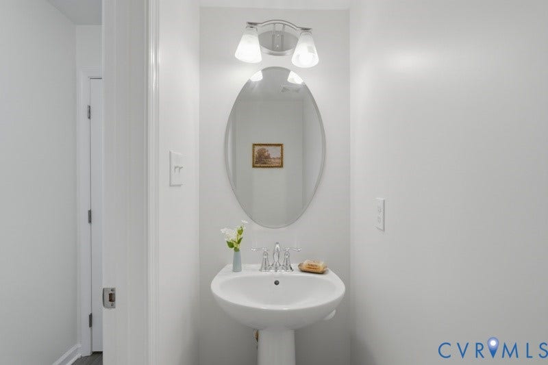 6012 Regal Crest Drive, Kings Grove, Chesterfield, VA 23832 Pedestal sink with chrome faucet, oval mirror, and wall-mounted light fixture