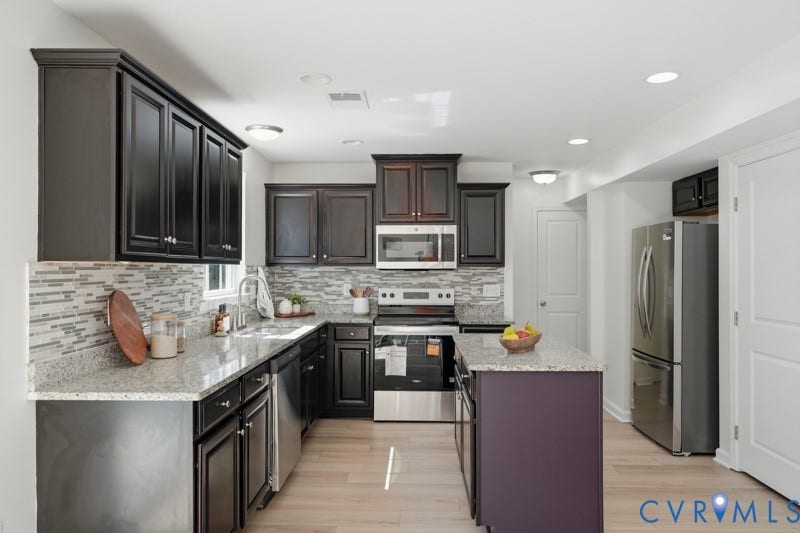 6012 Regal Crest Drive, Kings Grove, Chesterfield, VA 23832 Kitchen featuring dark wood cabinetry, light-toned granite countertops, a mosaic tile backsplash, stainless steel appliances, and a central island with a contrasting base