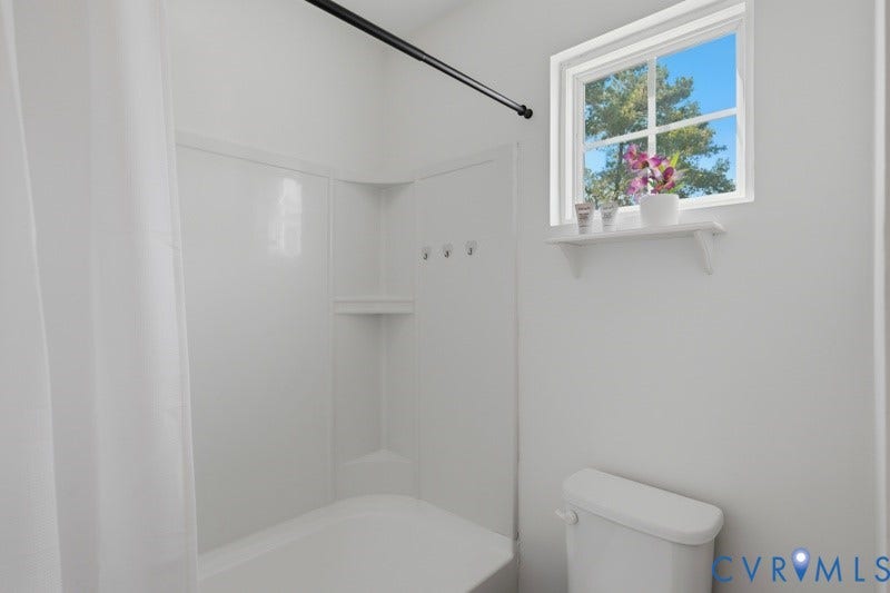 6012 Regal Crest Drive, Kings Grove, Chesterfield, VA 23832 White tub and shower combination with an integrated soap dish, a white-framed window, and a wall-mounted toilet