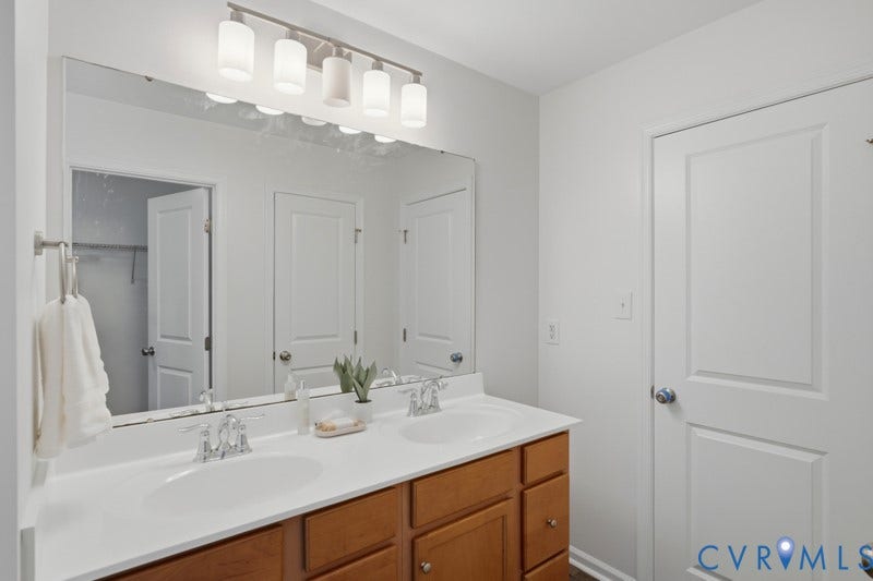 6012 Regal Crest Drive, Kings Grove, Chesterfield, VA 23832 Double vanity with integrated sinks, wood-finish cabinetry, chrome faucets, and an expansive wall mirror