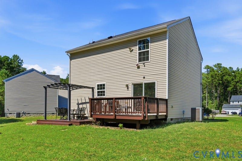 6012 Regal Crest Drive, Kings Grove, Chesterfield, VA 23832 Expansive backyard featuring a wood-finish deck, sliding glass doors, a large ground-level patio, and a pergola structure