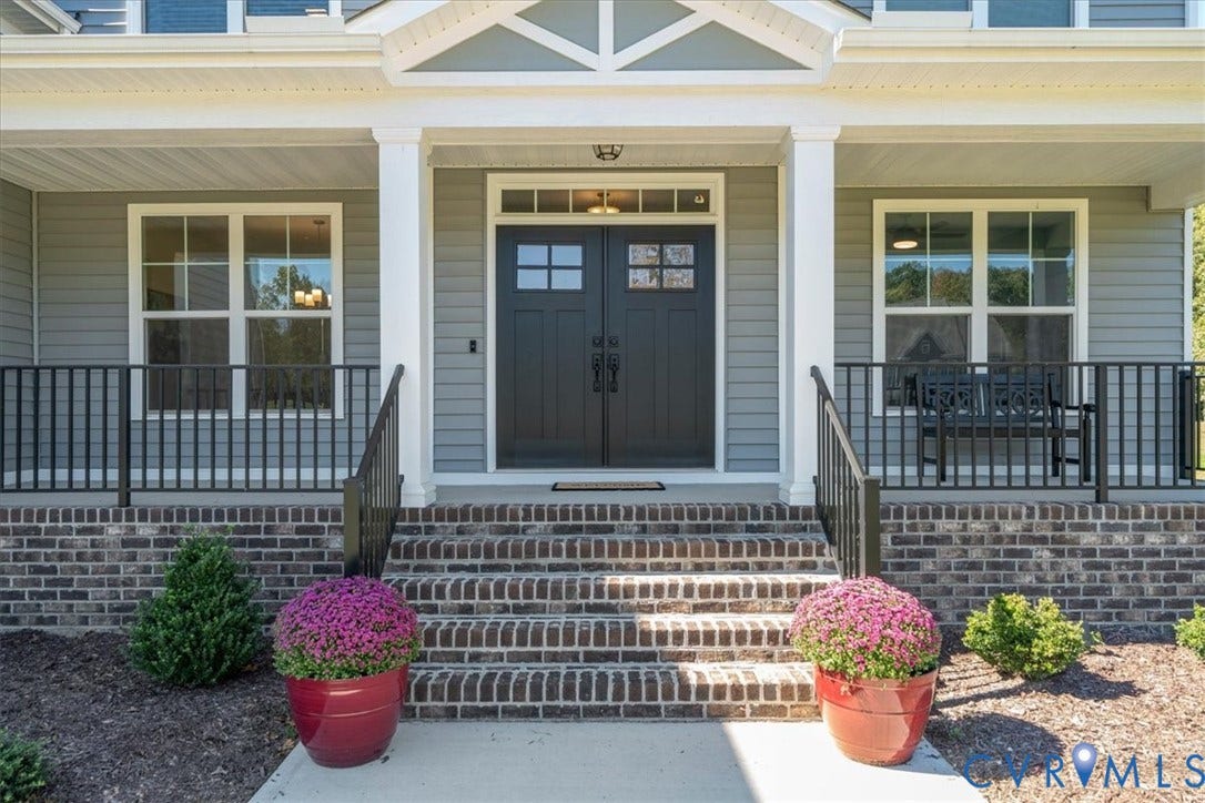 Front facade featuring a covered porch, brick steps, double entry doors with transom window, and architectural gables