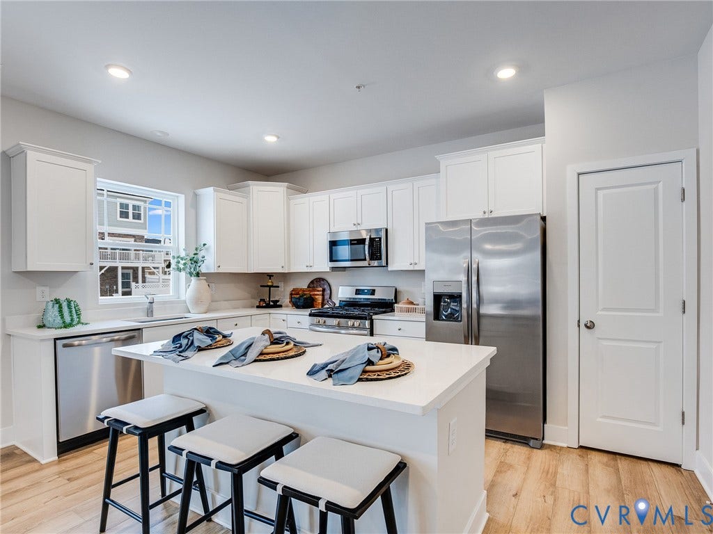 3724 Larimar Lane, Everstone, Richmond, VA 23223 Kitchen featuring white cabinetry, stainless steel appliances, an island with countertop seating, recessed lighting, and wood-finish flooring
