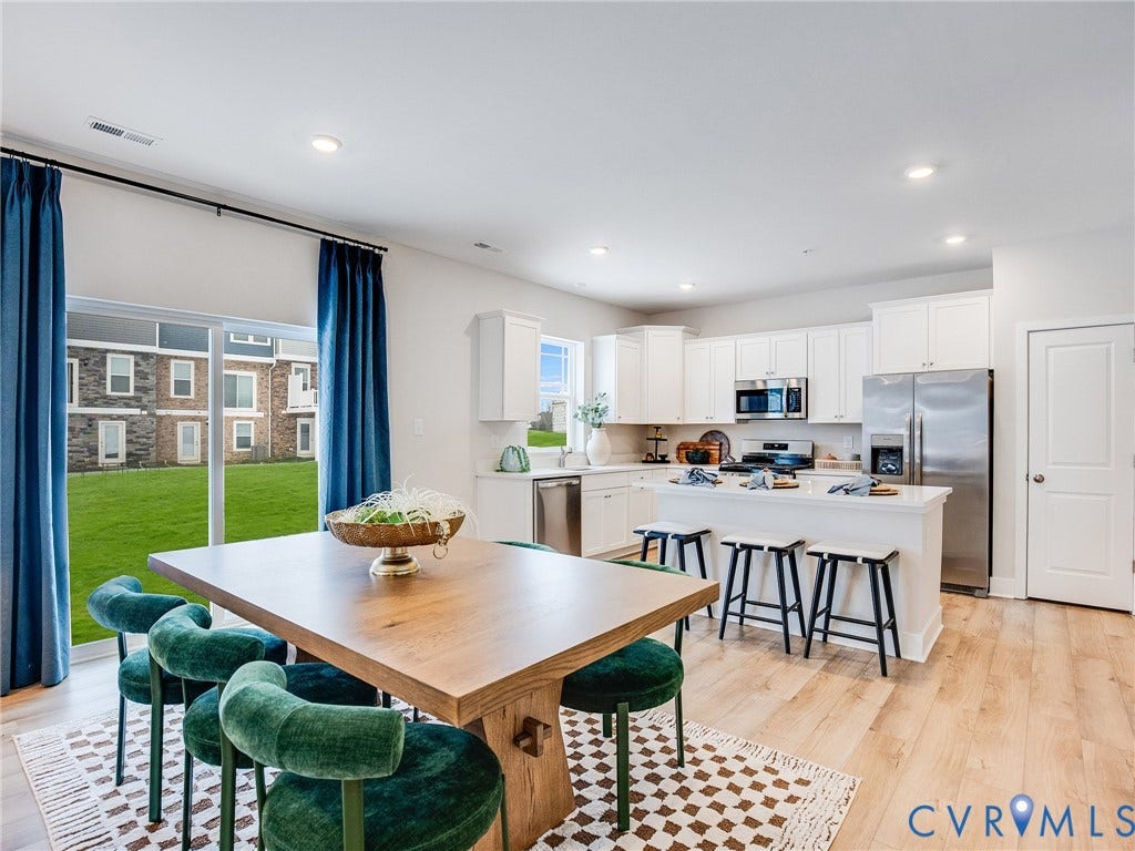 3724 Larimar Lane, Everstone, Richmond, VA 23223 Open-concept kitchen and dining area featuring light wood-finish flooring, white cabinetry, stainless steel appliances, and a kitchen island with seating