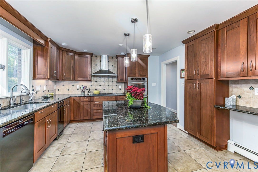 10309 Collinwood Drive, Henrico, VA 23238 Kitchen with custom cherry finish cabinetry, granite countertops, stainless steel appliances, tiled flooring, pantry and large kitchen island with pendant lighting above.