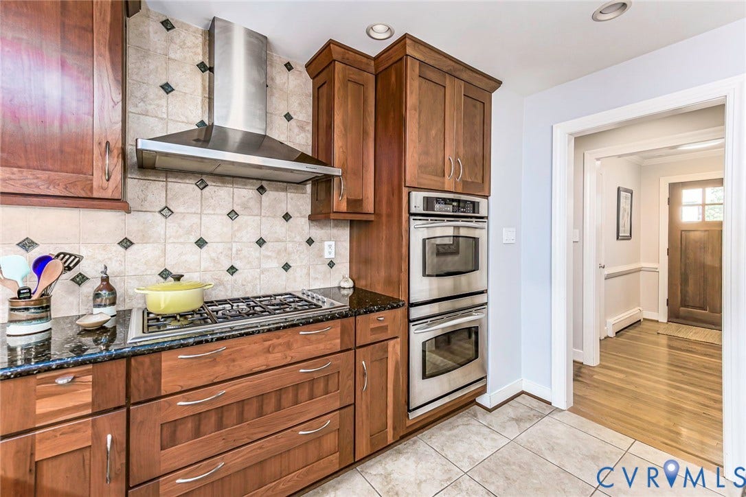 10309 Collinwood Drive, Henrico, VA 23238 Chef's kitchen featuring rich wood cabinetry, stainless steel dual wall ovens, gas cooktop with professional-grade range hood, granite countertops and decorative tile backsplash with coordinating accent tiles