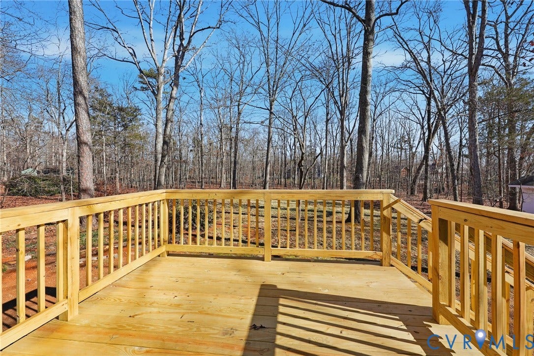 3264 Sherwood Ridge Way, Powhatan, VA 23139 Expansive composite deck with warm wood-finish flooring and custom railings, overlooking a wooded landscape of mature hardwood trees