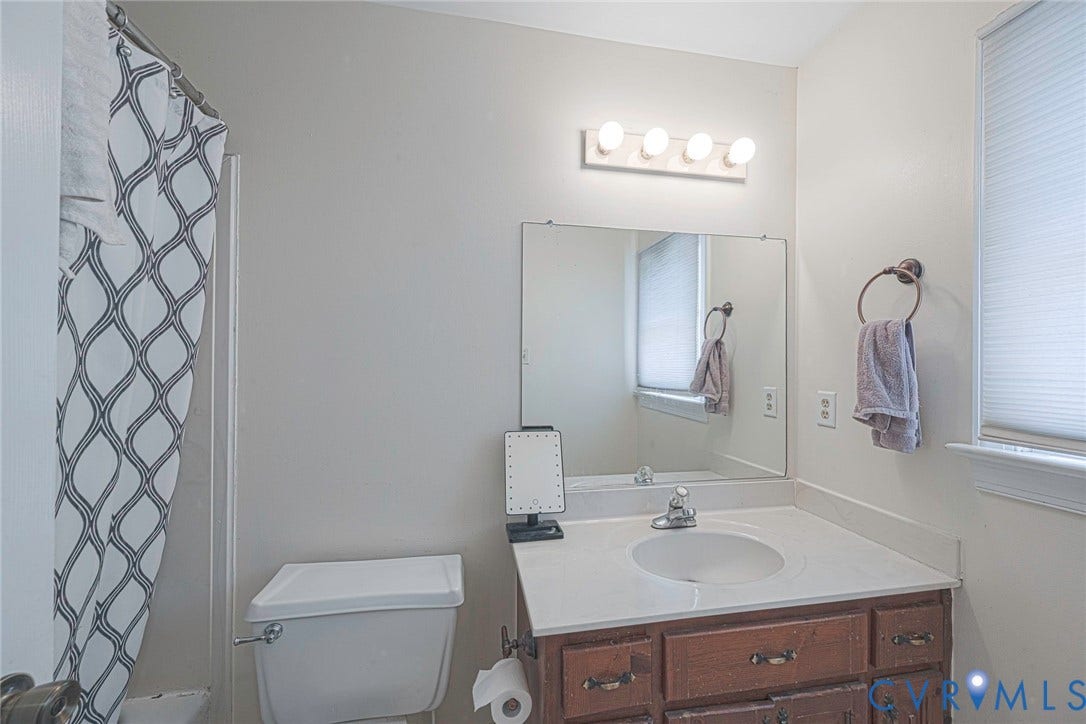 Vanity with a white countertop and integrated sink, bronze-finish faucet, and coordinating towel ring