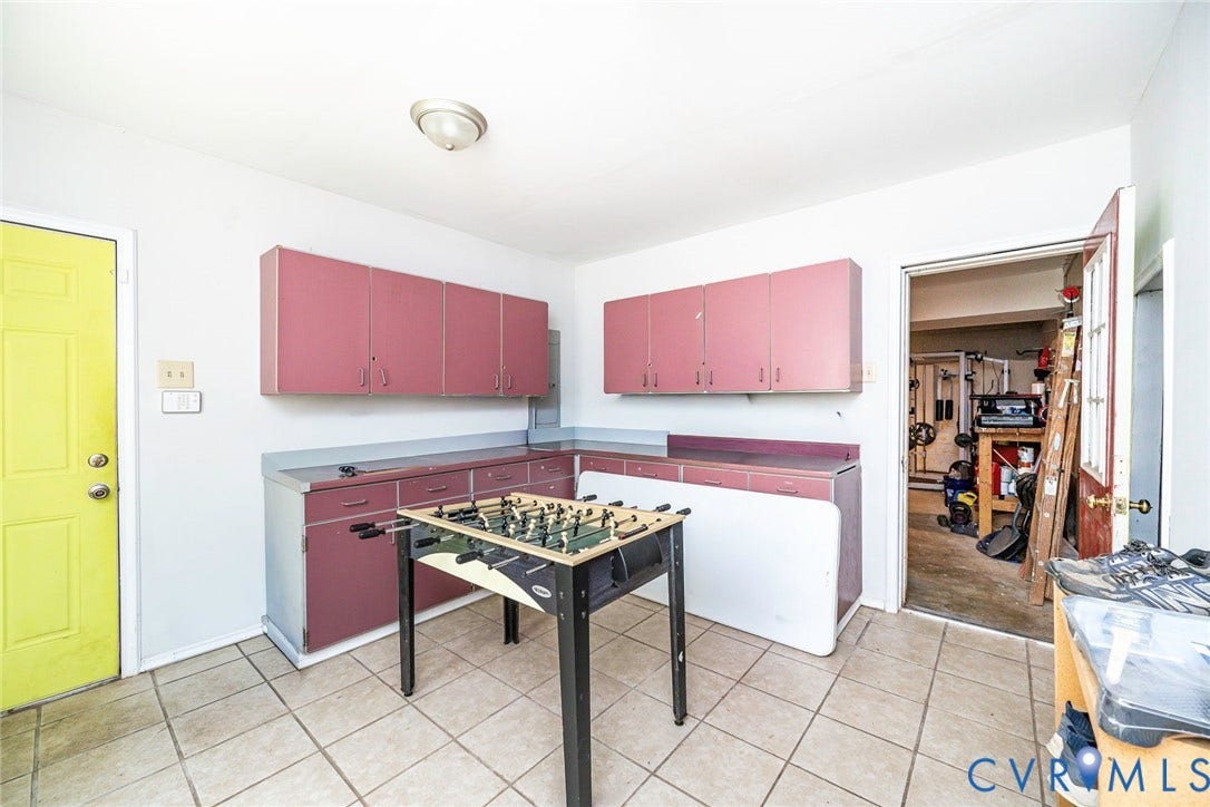 Functional room featuring extensive cabinetry, L-shaped countertop space, a tile floor, and a flush-mount ceiling light