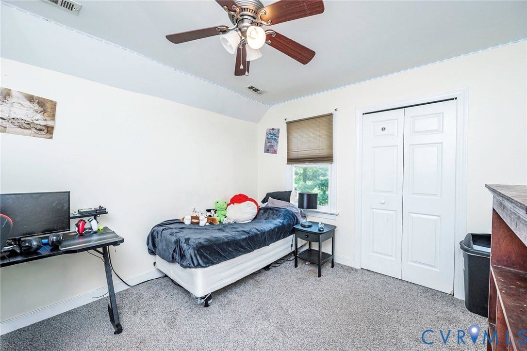 Spacious bedroom with wall-to-wall carpeting, ceiling fan with integrated lighting, dual closets with white panel doors, and a desk workspace
