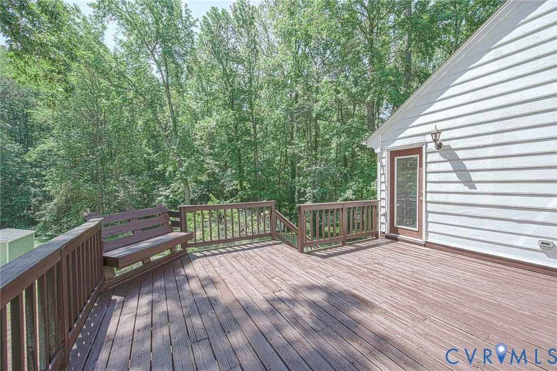 Expansive composite deck with wood-finish decking and dark wood railings, overlooking mature tree line