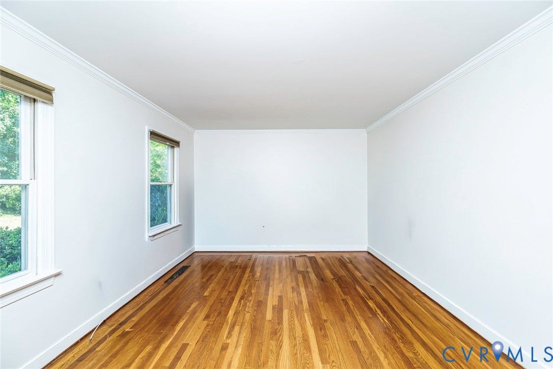 Bright, light-filled room featuring gleaming wood-finish flooring and crisp white walls