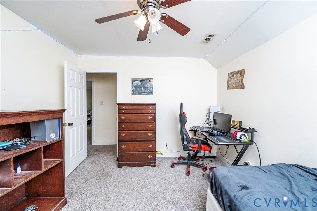 Spacious bedroom offering carpet flooring, ceiling fan with integrated lighting, and ample room for multiple furniture arrangements