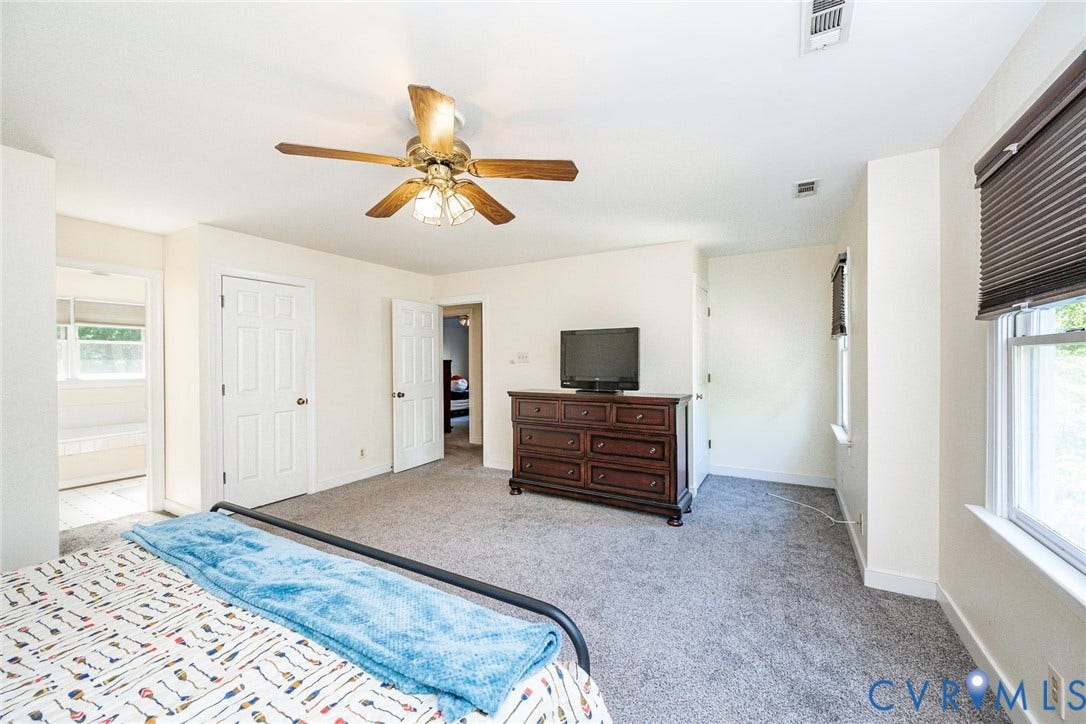 Carpeted room with a ceiling fan, multiple windows, and white trim throughout