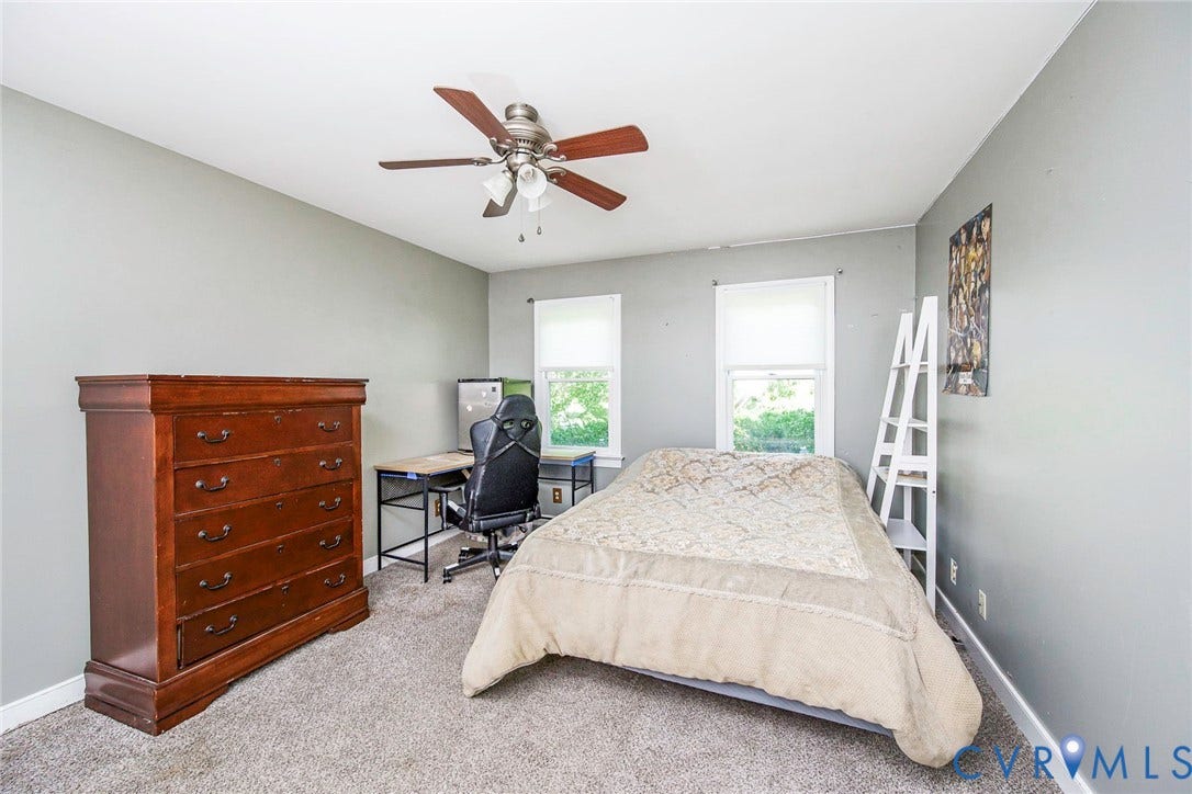 Carpeted flooring, two windows with window treatments, and a ceiling fan with integrated lighting