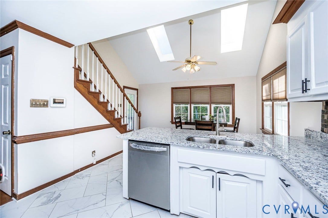 Kitchen featuring a peninsula with a double basin sink, light-colored cabinetry, and granite countertops