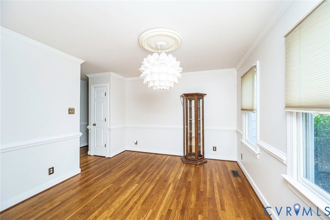 Hardwood flooring, crown molding, chair rail molding, ceiling medallion, and a decorative light fixture