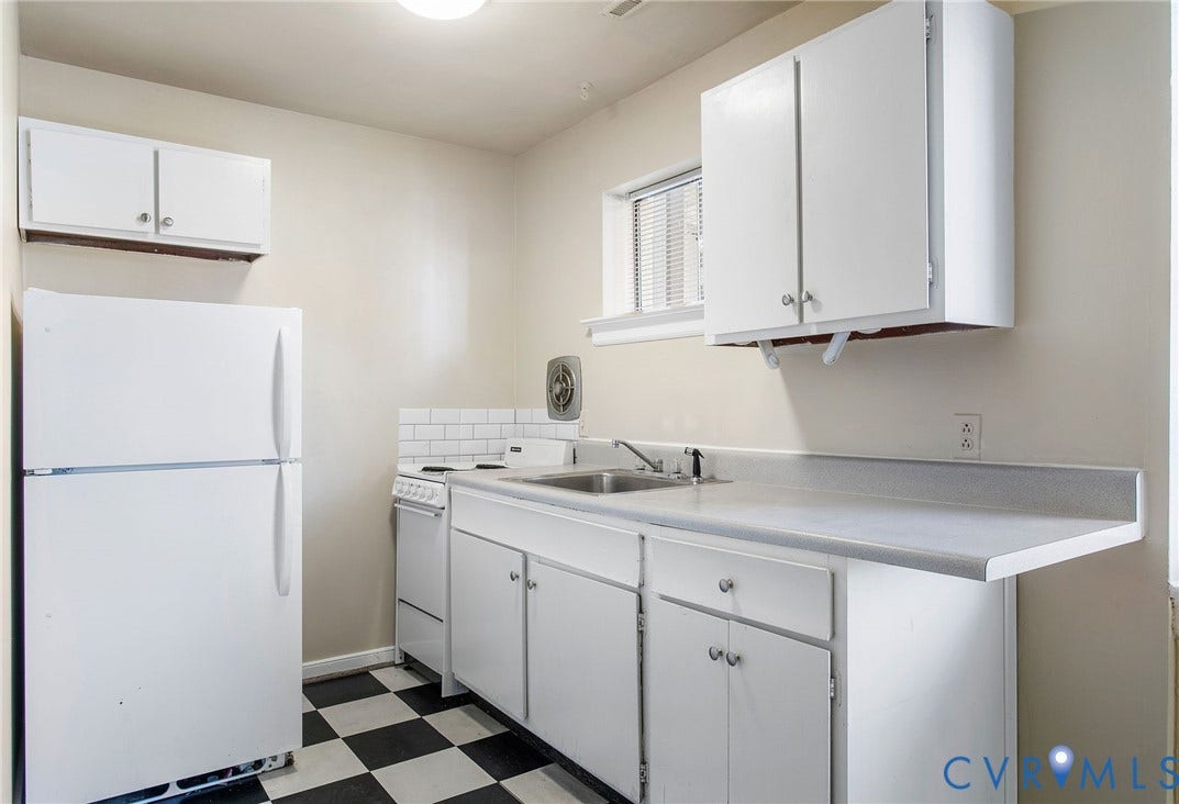 Compact kitchen featuring white cabinetry, a built-in sink, and a black and white checkered floor